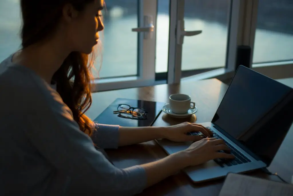A tightly cropped photo of a woman working on a Mac in twilight