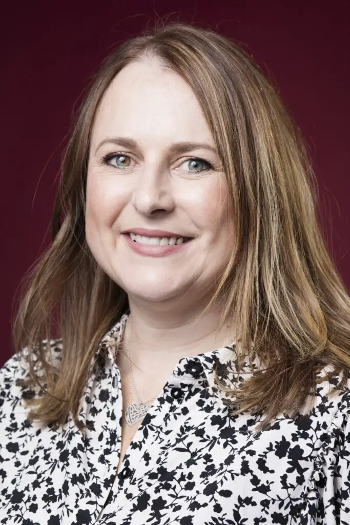 Close crop headshot of Natasha on dark maroon background