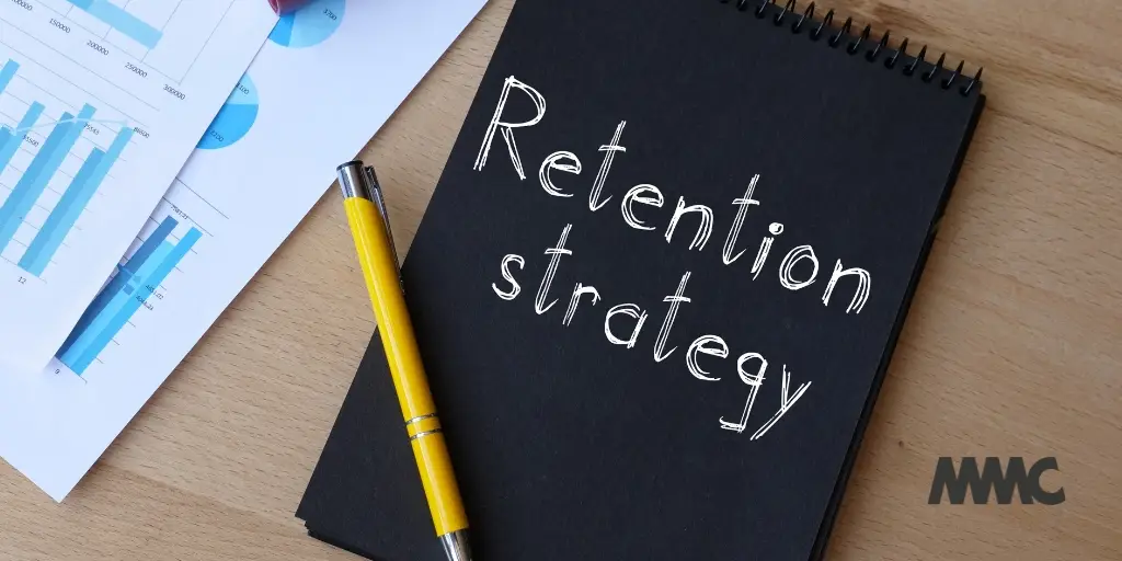 close crop photo of a blog notepad on wooden desk. Retention strategy is written in white on the ad and a yellow pen lies on top.