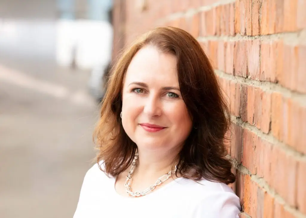 Close up photo of MMC owner Natasha McDonough leaning against a red brick wall.